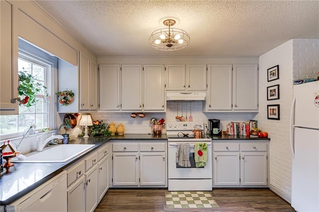kitchen with white appliances, under cabinet range hood, a sink, a textured ceiling, and a chandelier