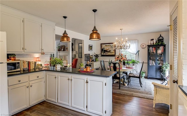 kitchen featuring dark countertops, stainless steel microwave, dark wood-style floors, and a chandelier