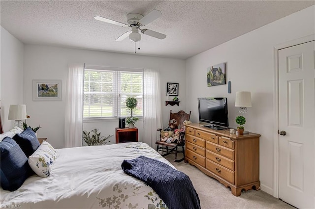 bedroom featuring light colored carpet, a textured ceiling, and ceiling fan