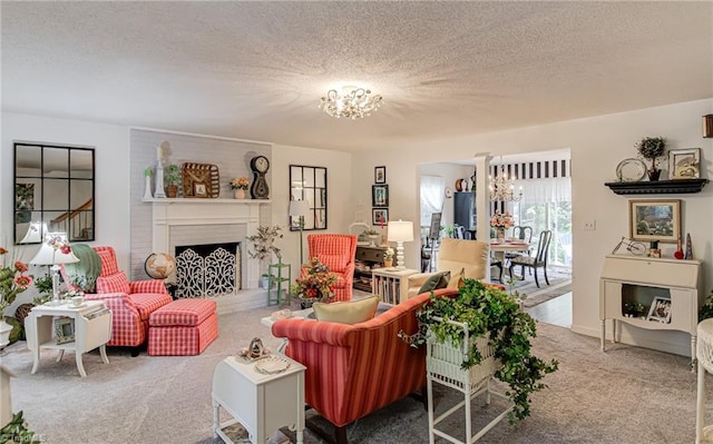 living room with a chandelier, carpet flooring, a textured ceiling, and a fireplace