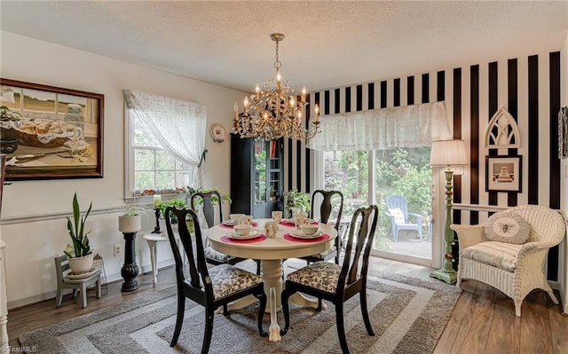 dining space with a chandelier, wood finished floors, and a textured ceiling