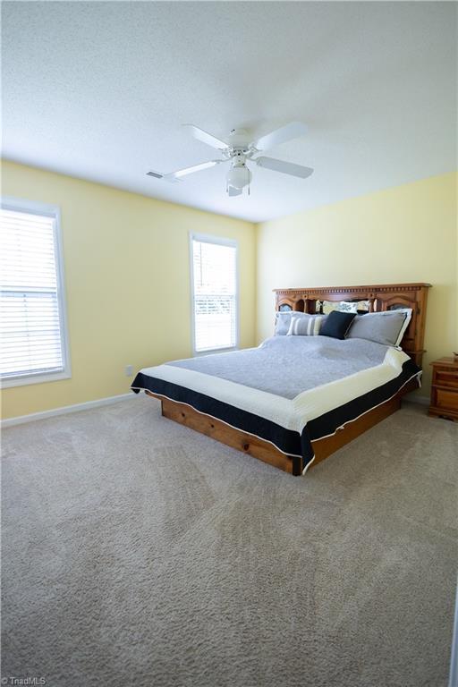carpeted bedroom featuring ceiling fan and baseboards