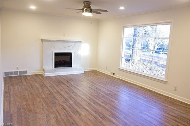 unfurnished living room featuring crown molding, ceiling fan, a high end fireplace, and dark hardwood / wood-style floors