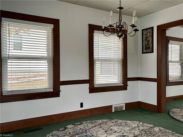 carpeted spare room with a chandelier and plenty of natural light