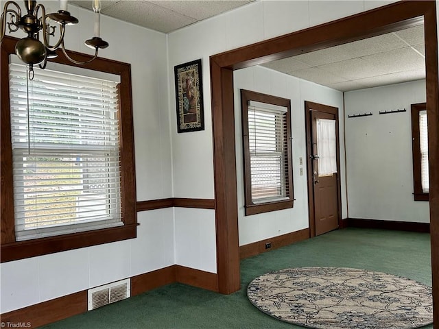 carpeted entrance foyer featuring an inviting chandelier