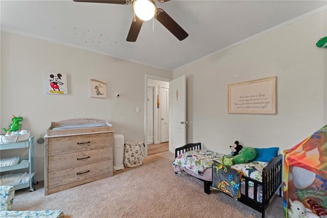 carpeted bedroom featuring ceiling fan and crown molding