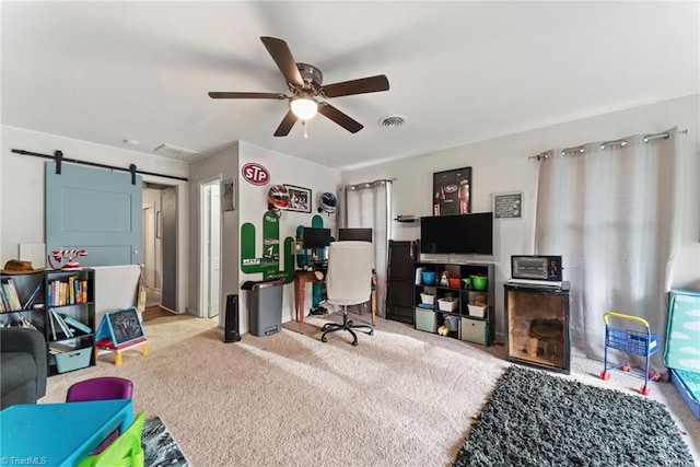 office with ceiling fan, a barn door, and light carpet