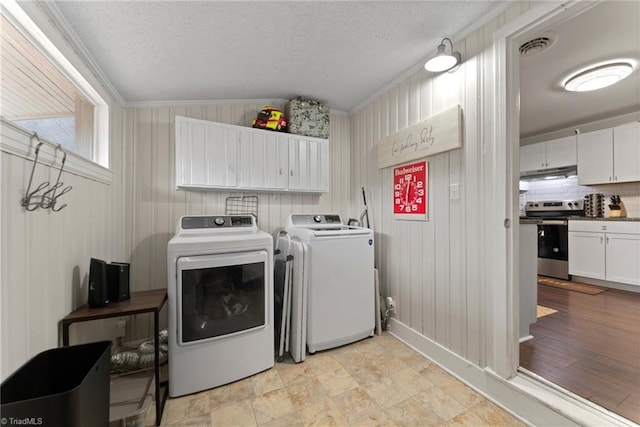 washroom with separate washer and dryer, light hardwood / wood-style flooring, wood walls, crown molding, and a textured ceiling