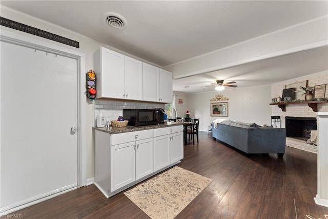 kitchen with white cabinets, dark hardwood / wood-style floors, ceiling fan, and a fireplace