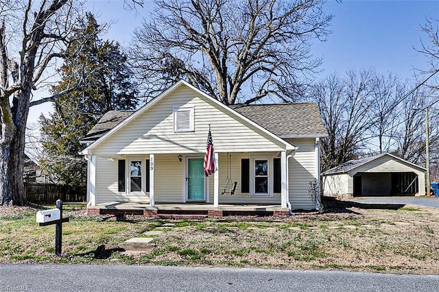 bungalow-style house featuring an outbuilding, a porch, a shingled roof, fence, and a garage