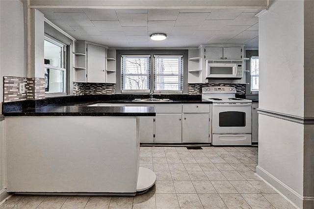 kitchen with white appliances, a sink, backsplash, open shelves, and dark countertops