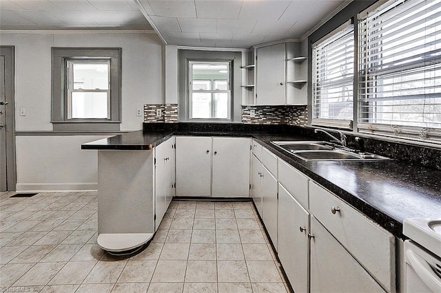 kitchen featuring a healthy amount of sunlight, decorative backsplash, open shelves, and a sink