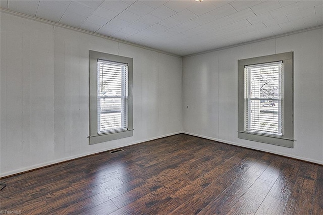 spare room featuring wood-type flooring, visible vents, a wealth of natural light, and ornamental molding