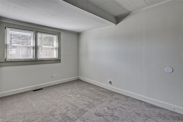 carpeted spare room with visible vents, beam ceiling, and baseboards