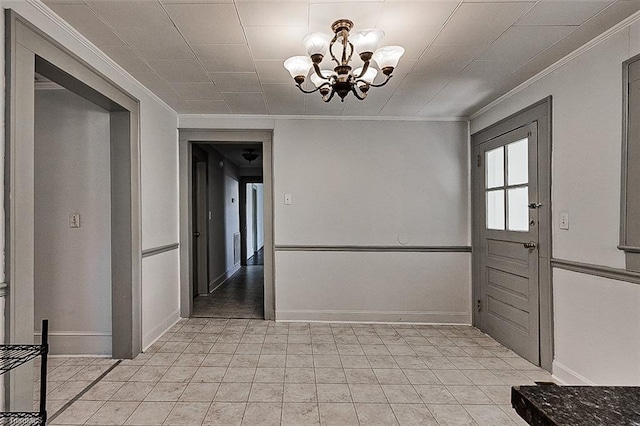 unfurnished dining area featuring ornamental molding, baseboards, and an inviting chandelier