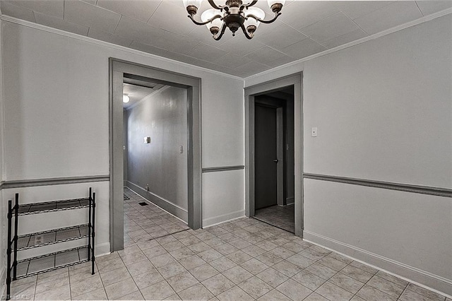 spare room with a chandelier, ornamental molding, and baseboards