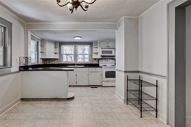 kitchen with crown molding, open shelves, dark countertops, an inviting chandelier, and white appliances