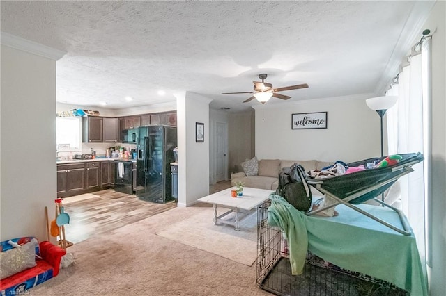 living area with crown molding, a textured ceiling, ceiling fan, and light colored carpet