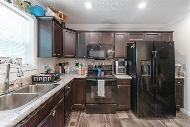 kitchen with crown molding, dark brown cabinetry, light countertops, a sink, and black appliances