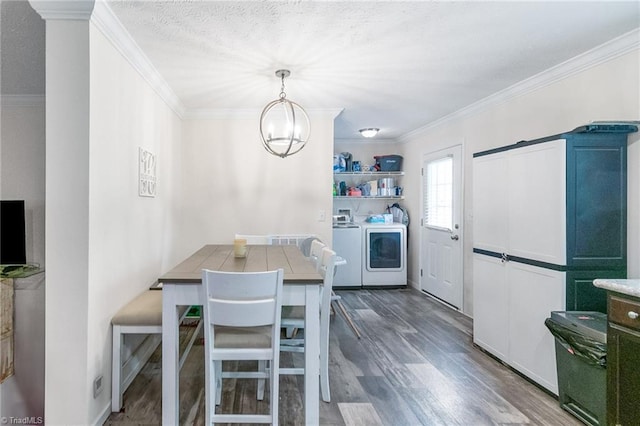 dining area featuring crown molding, an inviting chandelier, washing machine and dryer, and wood finished floors