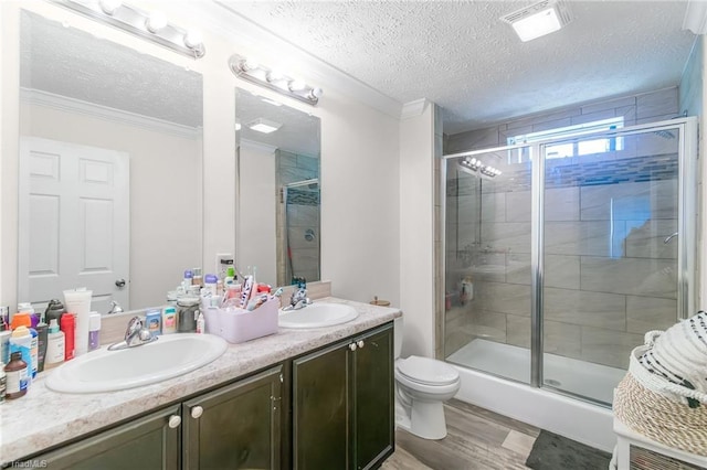 bathroom with wood finished floors, a sink, a stall shower, and double vanity
