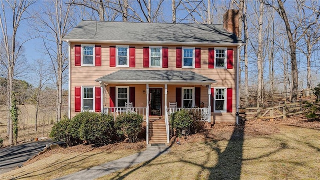 colonial home featuring covered porch and a chimney