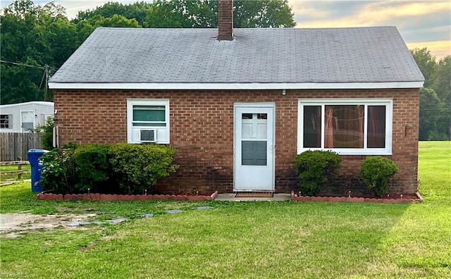 view of front of property featuring cooling unit and a yard