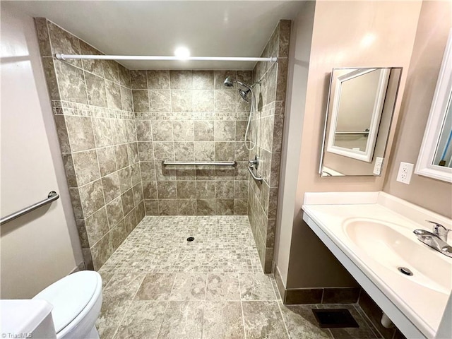 bathroom featuring vanity, toilet, tile patterned floors, and a tile shower