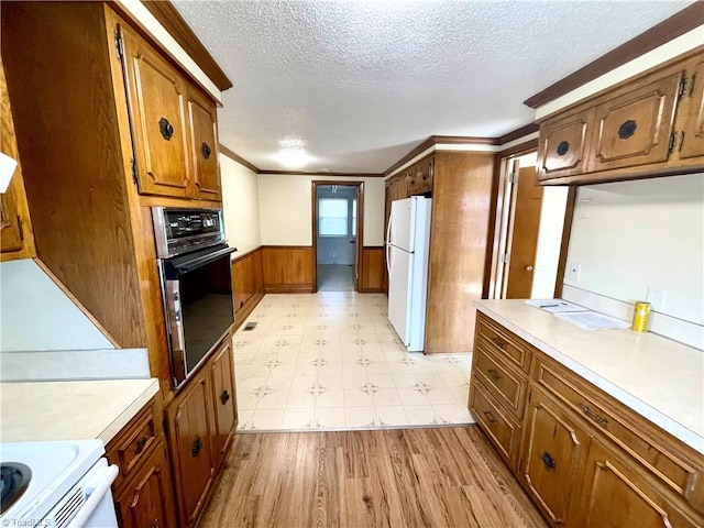 kitchen with range, light hardwood / wood-style flooring, black oven, a textured ceiling, and white refrigerator