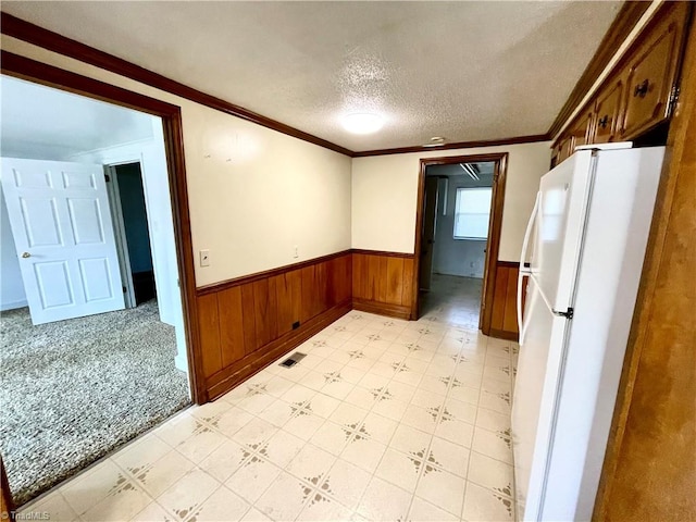 kitchen with a textured ceiling, light tile patterned flooring, white refrigerator, and crown molding