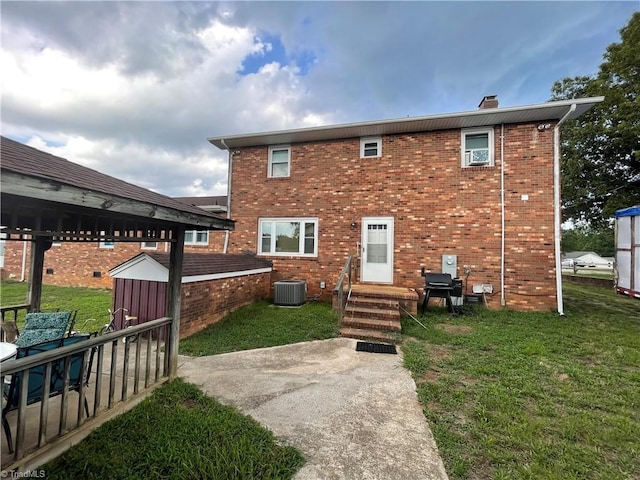 rear view of property with central air condition unit, a shed, a patio, and a lawn