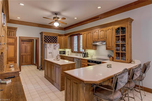 3705 Bradwyck Cir, Winston-Salem, NC 27104 - kitchen with stainless steel appliances, light countertops, brown cabinetry, a kitchen island, and a ceiling fan