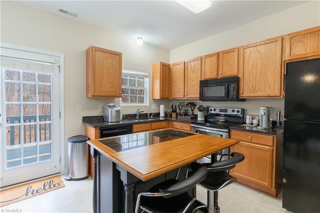 kitchen featuring a wealth of natural light, a breakfast bar, sink, and black appliances