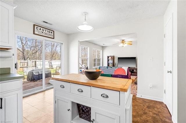 kitchen with a textured ceiling, ceiling fan, butcher block counters, visible vents, and white cabinets