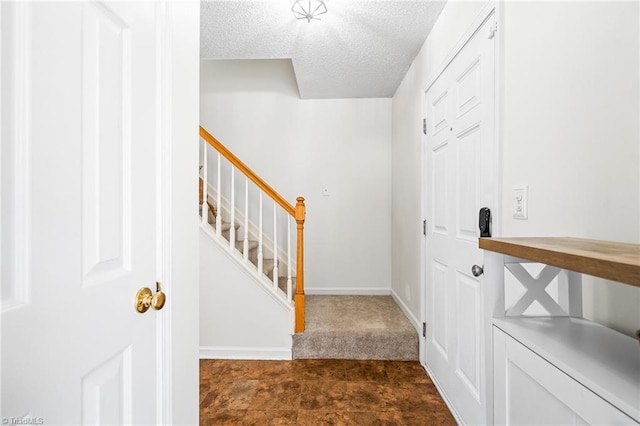 foyer entrance featuring a textured ceiling, baseboards, and stairs