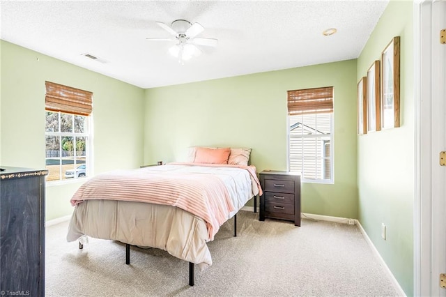 carpeted bedroom featuring visible vents, ceiling fan, a textured ceiling, and baseboards