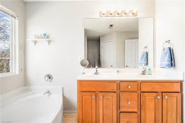 bathroom with a garden tub, a sink, visible vents, and double vanity