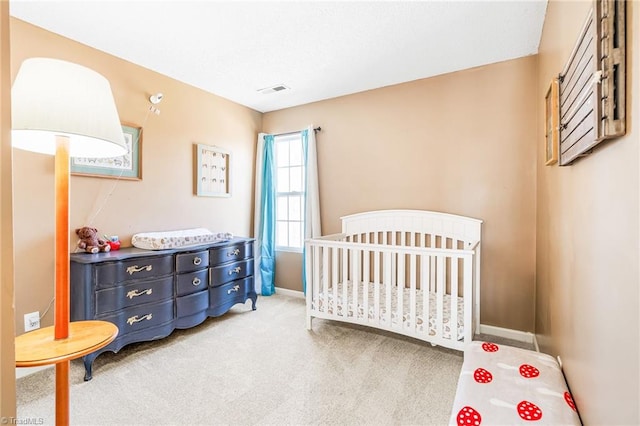 carpeted bedroom featuring a crib, visible vents, and baseboards