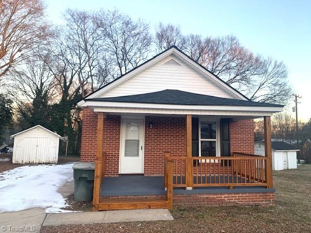 bungalow-style house with covered porch and a storage shed