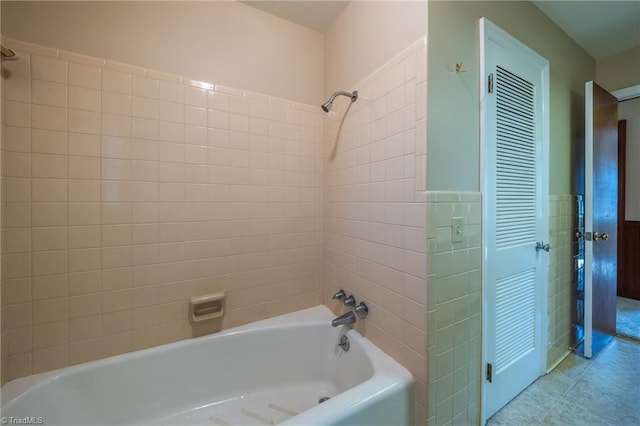 full bath with tile patterned floors, shower / bath combination, tile walls, and a wainscoted wall