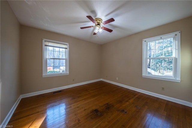 spare room with visible vents, baseboards, dark wood finished floors, and a ceiling fan