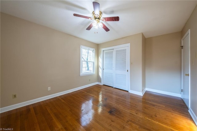 unfurnished bedroom featuring a closet, baseboards, a ceiling fan, and hardwood / wood-style flooring