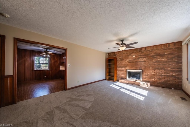 unfurnished living room featuring visible vents, carpet floors, a fireplace, ceiling fan, and a textured ceiling