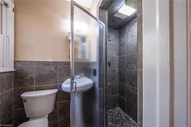 bathroom featuring a shower stall, toilet, tile walls, and wainscoting