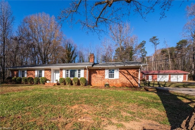 ranch-style home featuring brick siding, a front yard, a chimney, a garage, and an outbuilding