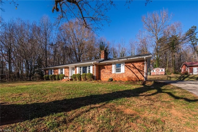 view of front of property featuring brick siding, an outbuilding, a front lawn, and a chimney