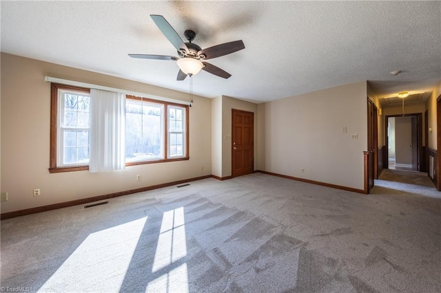 spare room featuring visible vents, a ceiling fan, a textured ceiling, light colored carpet, and attic access