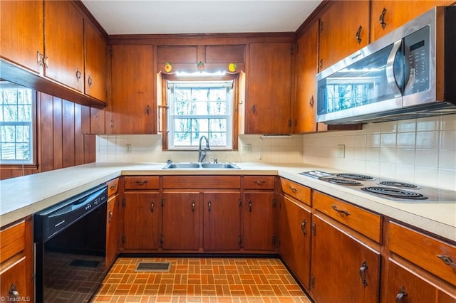 kitchen featuring a sink, stainless steel microwave, electric stovetop, light countertops, and dishwasher