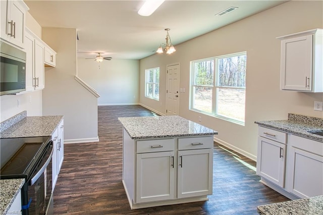 kitchen with appliances with stainless steel finishes, white cabinets, decorative light fixtures, and visible vents