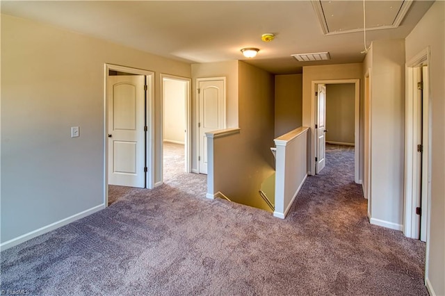 empty room featuring attic access, visible vents, carpet floors, and baseboards